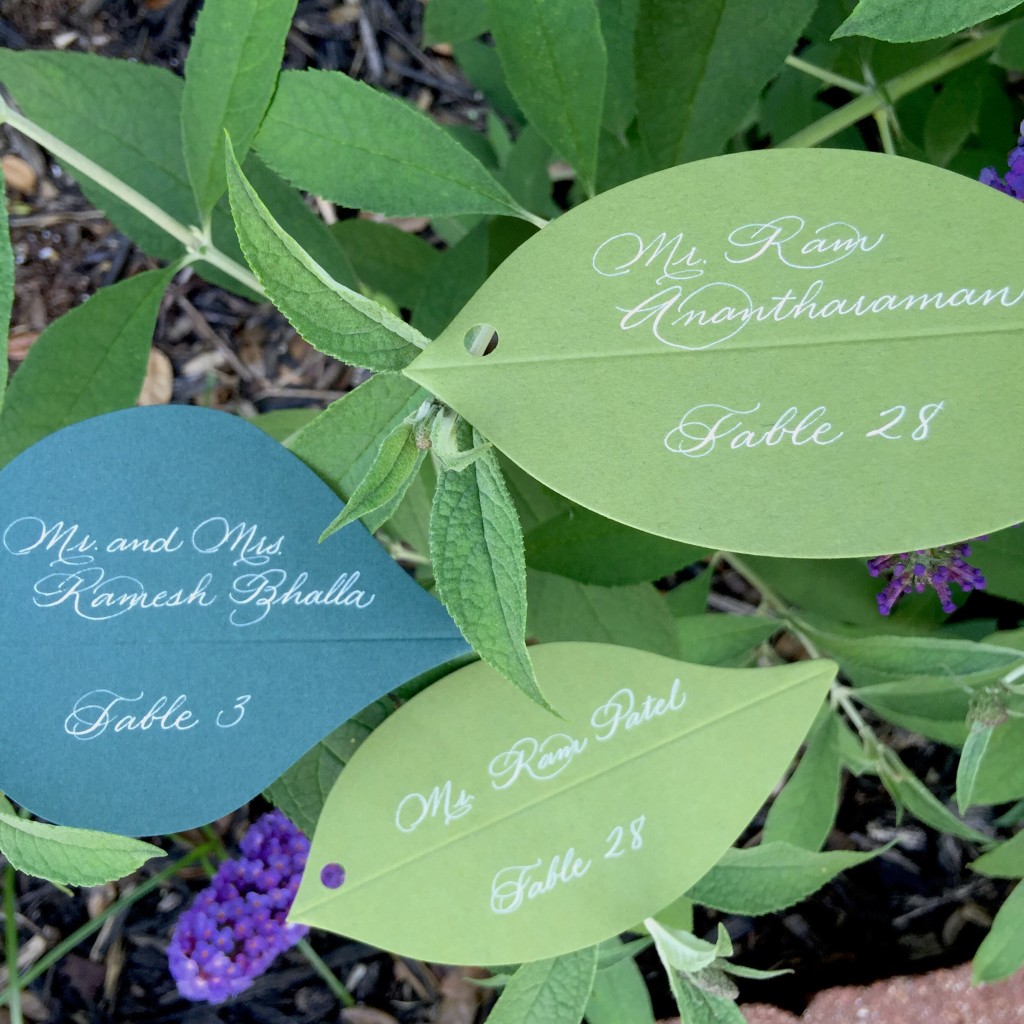 white and green escort card calligraphy on leaves