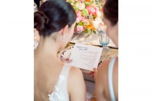 bride holding menu card with wedding calligraphy looking at it