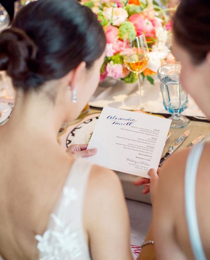 bride holding menu card with wedding calligraphy looking at it
