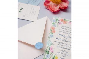 invitation with modern calligraphy surrounded by bright handpainted florals