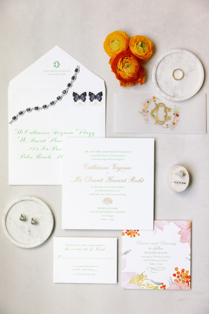Ritz Carlton Dallas wedding invitations on a table with orange flowers.