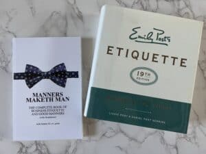 a photo of etiquette books on a table, emily post and manners maketh the man with the bow tie on the cover