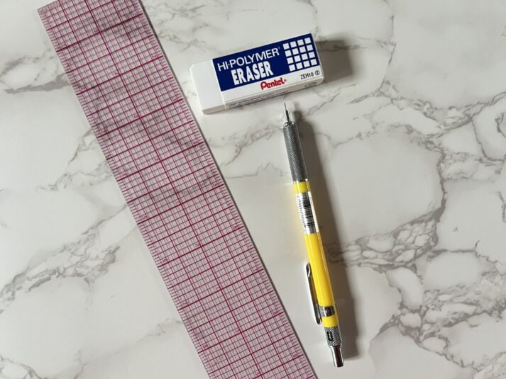 clear ruler with red grid lines, white rubber eraser and yellow mechanical pencil
